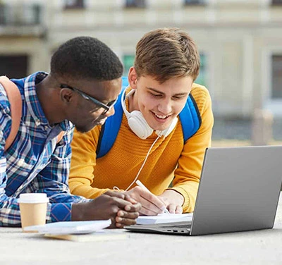 Two male college students using laptop on campus